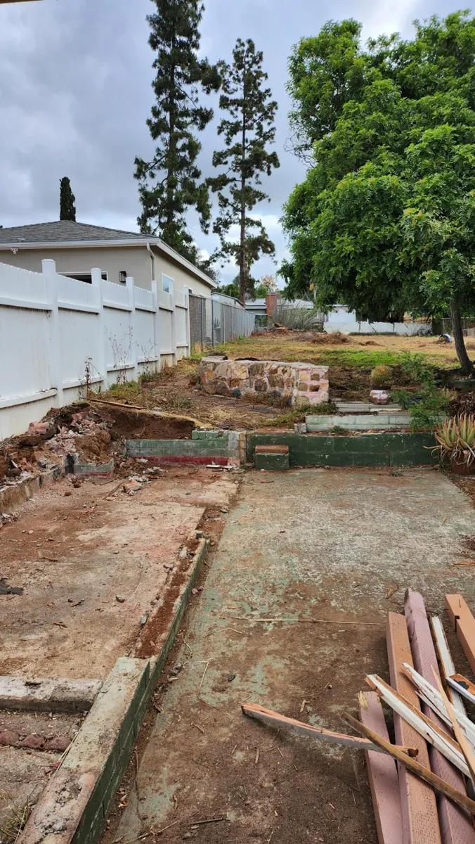 Existing backyard concrete pads and masonry landscape walls before demolition