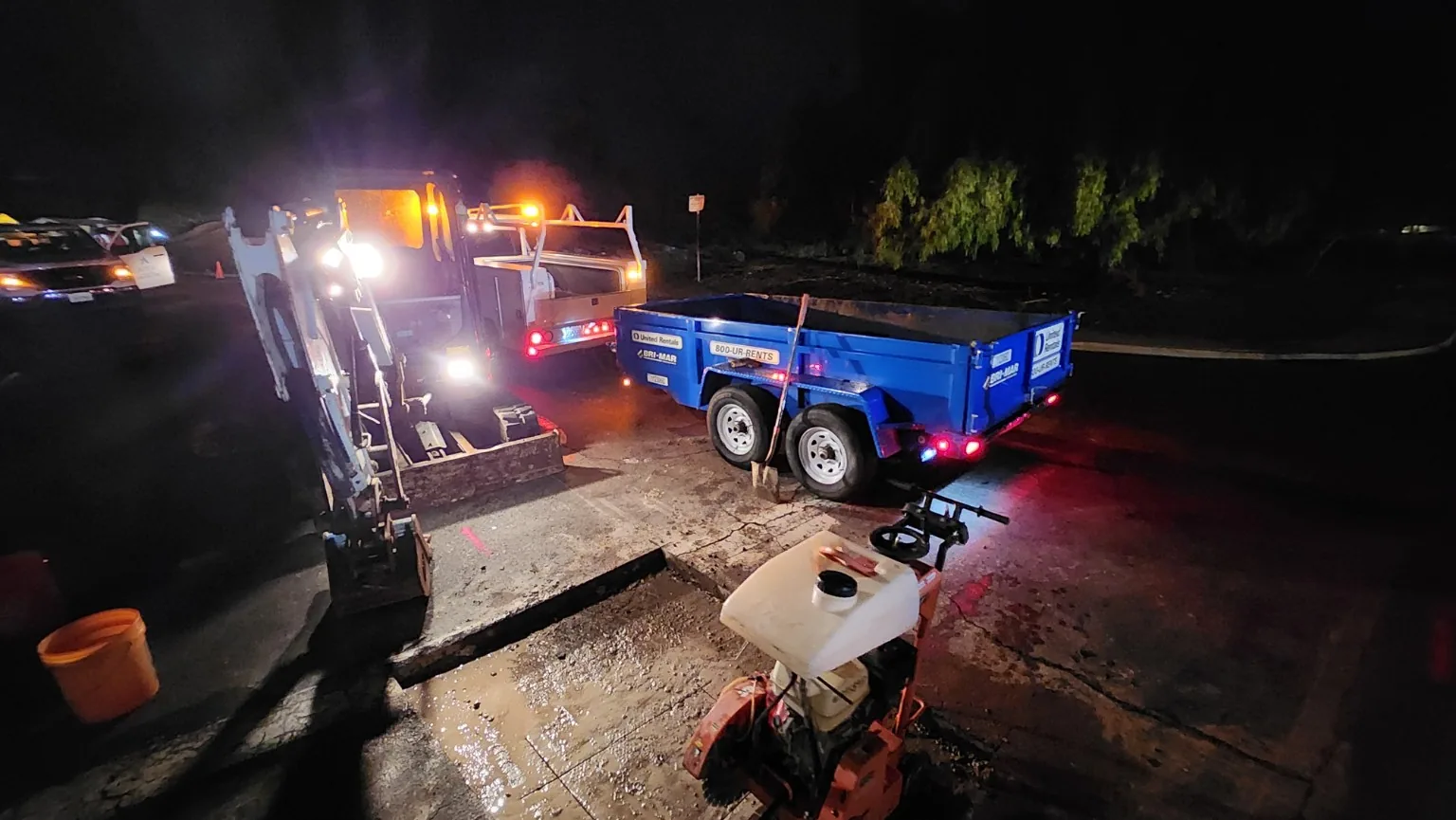 Night roadway work zone with equipment and temporary traffic delineation